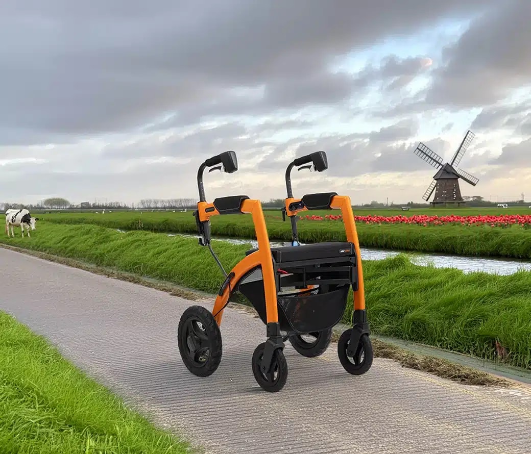 De oranje Rollz Motion Performance op een fietspad tussen weilanden, met een koe, een tulpenveld en een molen op de achtergrond.