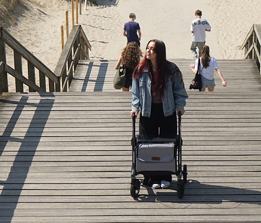 Een jonge vrouw loopt met de Rollz Air over een houten vlonder bij het strand