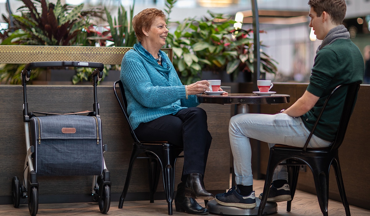 Vrouw die koffie drinkt met haar zoon na een wandeling in het winkelcentrum met een Rollz Flex rollator
